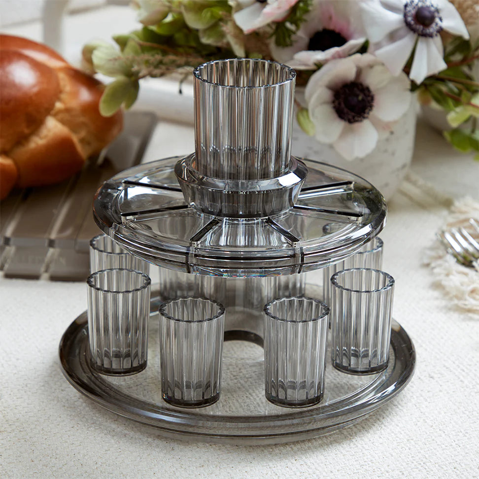 The Apeloig Kiddush Wine Fountain Set features a round, two-tiered design with eight ribbed shot glasses—an elegant piece of Judaica for your collection, perfect for sharing wine at your Shabbat or holiday table.
