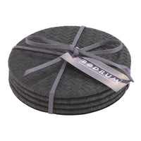 The Bodrum Wicker Easy Care Coaster Set includes four round black wicker coasters tied with a gray ribbon, featuring a tag with the Bodrum brand name.