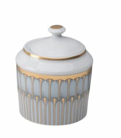 A white porcelain jar with lid, adorned with gold geometric patterns, inspired by the elegance of Arcades Gold Dinnerware from Philippe Deshoulieres.