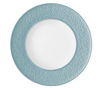 The Mineral Irise Dinnerware Sky Blue by Raynaud features a round white Limoges porcelain plate with a wide, textured sky blue rim and smooth center, showcasing elegant modern style with its subtle, wavy border pattern.