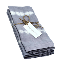 The Hand Dyed Linen Napkin Set of 4 in Lavender Gray by Whigstock Studio, tied with twine and a branded tag, offers a perfect sustainable essential for your table.