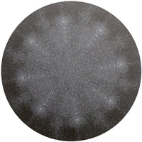 The Shagreen Placemat by Tisch New York features an intricate, circular design of small white cell-like dots radiating symmetrically from the center, creating a textured starburst effect on a dark gray background.