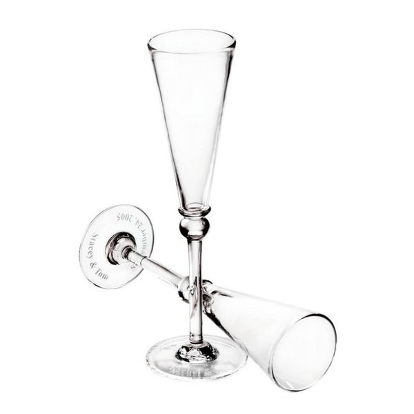 The Simon Pearce Hartland Flute Set of 2 features two clear handmade glasses, one upright and one horizontal with interlocked stems, displayed empty on a white background—an elegant and memorable wedding gift.