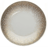 The Souffle D'or Dinnerware by Haviland is a round Limoges porcelain plate with a white center and a border of gold, silver, and bronze dots creating a gradient from the rim to the middle.