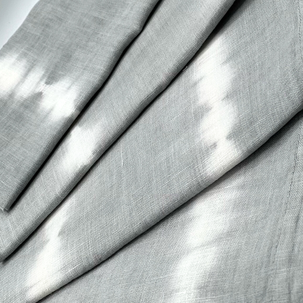 Close-up of Whigstock Studio’s Hand Dyed Linen Napkin Set of 4 in Pebble—gray napkins with soft white streaks and a textured, woven look.