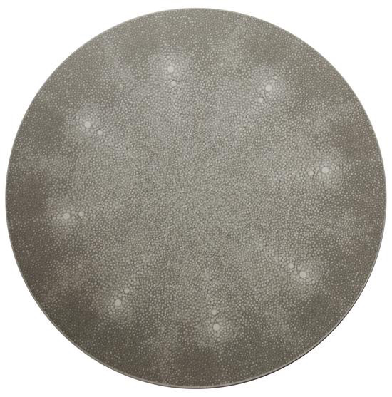 The Shagreen Placemat Grey Set of 4 by Tisch New York features round, flat mats with a textured gray surface and subtle white dots, resembling a sea urchin shell—perfect as unique placemats for elegant table decor.