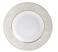 The Bernardaud Sauvage Gold Dinnerware features a white Limoges porcelain plate with a textured, light-patterned rim resembling embossed snake skin and finished with thin gold bands for an elegant, minimal design.