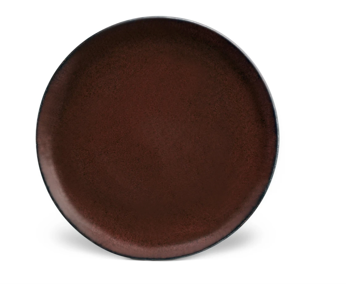The Terra Wine Dinnerware by L'Objet is a handcrafted, round ceramic plate in dark brown with a lightly textured surface, shown against a plain white background.