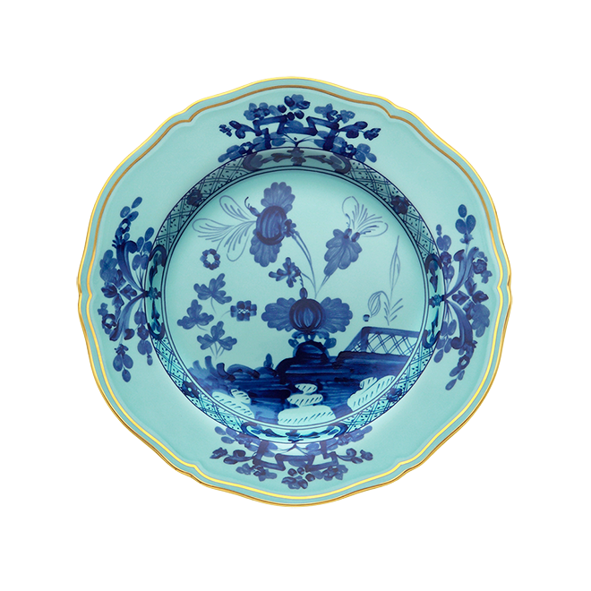 The Ginori 1735 Oriente Italiano Dinnerware Iris is a round ceramic plate with a scalloped edge, turquoise background, yellow rim, and detailed blue chinoiserie floral motifs inspired by Italian porcelain.