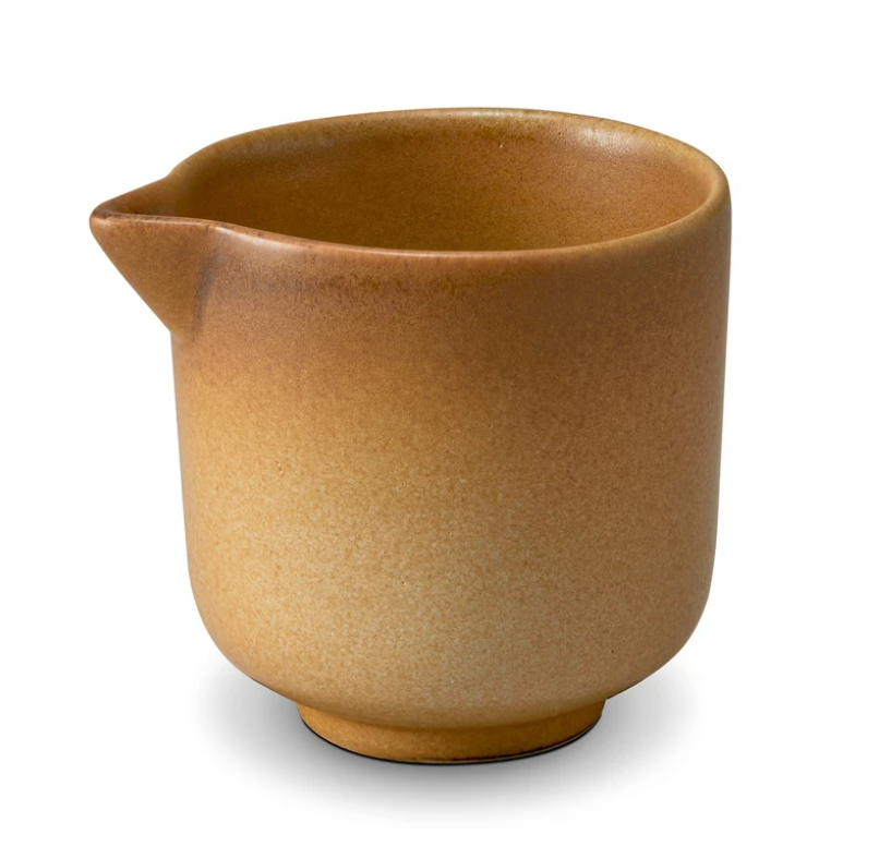 The Terra Leather Dinnerware pitcher from L'Objet is a small, round, brown ceramic piece with a smooth gradient finish and spout, showcasing hand-crafted artistry against a white background.