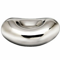 The Bean Silver Bowl from Inspired Generations is a shiny, metallic, bean-shaped piece with a smooth reflective surface and a concave depression in the center, featuring a distinctive silver accent that highlights its modern design.