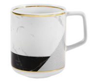 The Carrara by Coline Le Corréa Dinnerware from Vista Alegre is a white ceramic mug with a Carrara marble pattern, gold-trimmed rim and base, diagonal black section with fine white lines, and a rectangular handle—a chic designer piece.