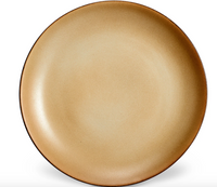 The L'Objet Terra Leather Dinnerware features a round, beige ceramic plate with a gentle gradient—darker edges and lighter center—highlighting its hand-crafted, glazed finish against a white background.