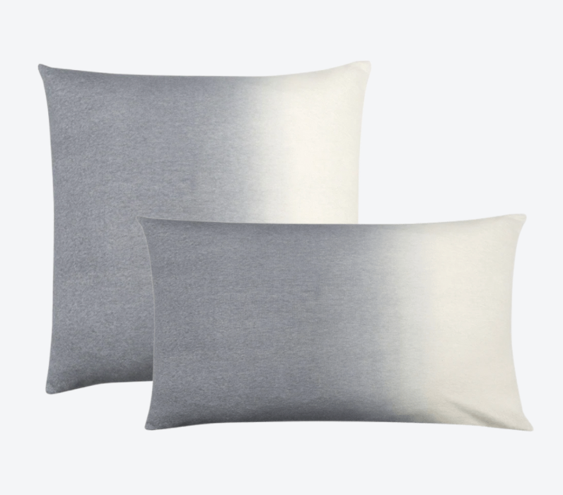 Two Johanna Howard Dip Dye Pillow Light Grey pillows—one square, one rectangular—feature a stylish ombré from gray to white and are displayed overlapping on a light gray background, perfect for anyone seeking a refined dip-dyed accent.