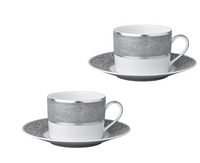 Two Bernardaud Sauvage Grey & Platinum teacups with handles and matching saucers, each adorned with a silver-gray platinum band resembling snakeskin. Elegant Limoges porcelain set on a plain white background.