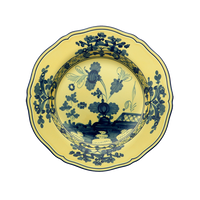 The Oriente Italiano Dinnerware Citrino by Ginori 1735 is a round, yellow ceramic plate with scalloped edges, adorned with a dark blue chinoiserie floral and geometric motif inspired by classic Ginori Oriente designs.