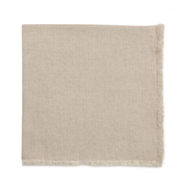 The Deborah Rhodes Herringbone Fringe Napkin Flax Set of 4 features light beige napkins with a subtle herringbone pattern and short fringe, reminiscent of a throw blanket, displayed on a white background.