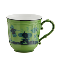 The Ginori 1735 Oriente Italiano Dinnerware Malachite is a green porcelain mug with a decorative black handle, featuring floral and abstract dark blue patterns on white—an exquisite example of Italian craftsmanship.