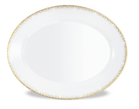 The Haviland Souffle D'or Dinnerware features a white oval porcelain plate with a gold-speckled rim, elegantly displayed on a white background.