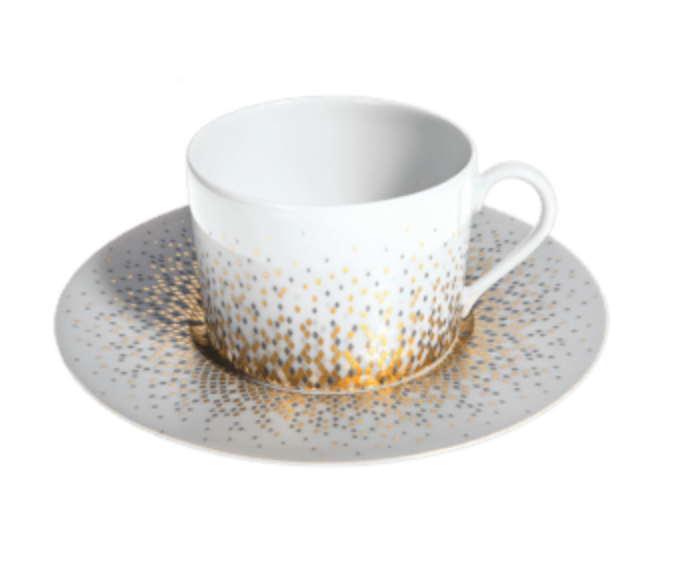 The Haviland Souffle D’or teacup and saucer are crafted from white Limoges porcelain, featuring a gold and silver dotted pattern that creates a radiant effect. The cup has a simple handle and sits centered on the matching saucer.