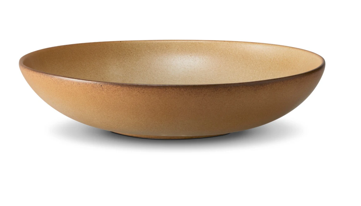 The Terra Leather Dinnerware by L'Objet is a wide, shallow, round ceramic bowl with a matte brown finish, beautifully hand-crafted and shown against a white background.
