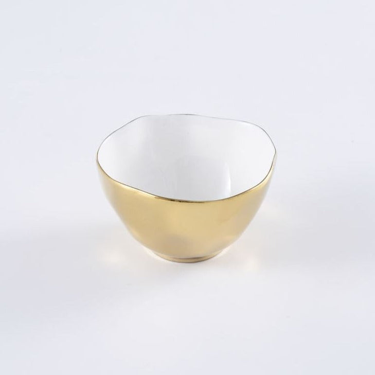 The Moonlight Snack Bowl by PAMPA BAY is a small, round white porcelain bowl with a slightly uneven rim, glossy white interior, and shiny gold titanium exterior, shown on a plain white surface.