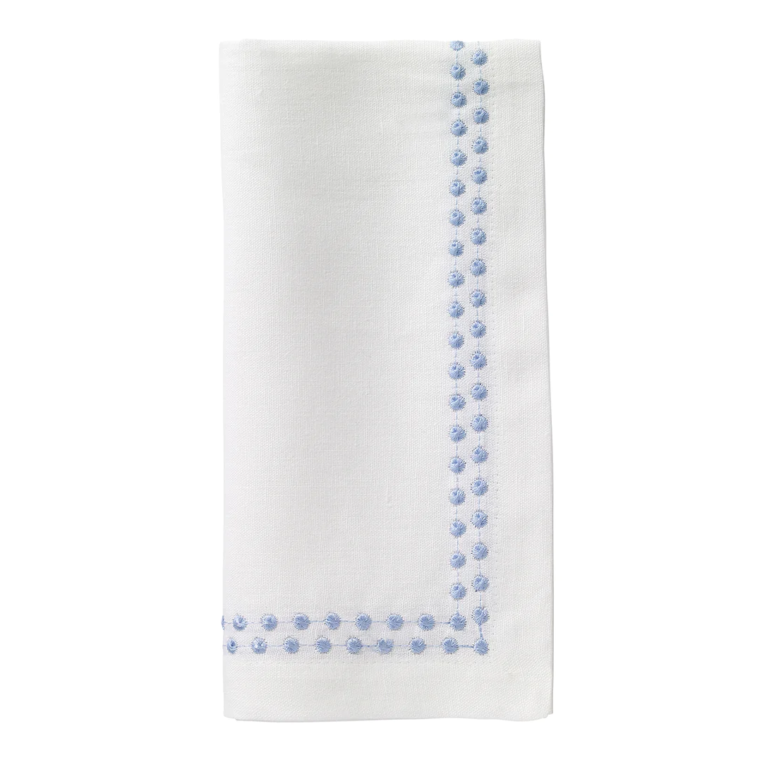 The Bodrum Pearls Napkin Ice Blue Set of 4 features off-white linen napkins with light blue embroidered dots forming an L-shaped border along two edges near the corner.
