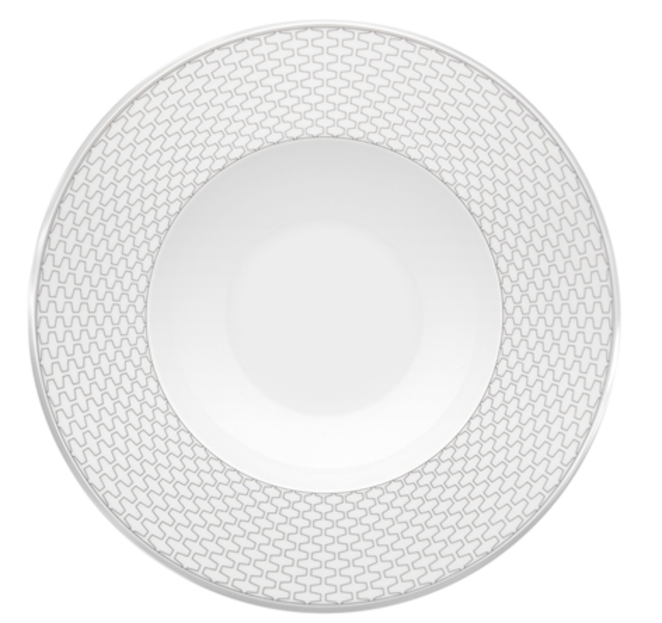 The Trasso Dinnerware by Vista Alegre is a round white porcelain plate with a wide rim featuring an interlocking light gray geometric zigzag pattern, while the center remains elegantly plain.