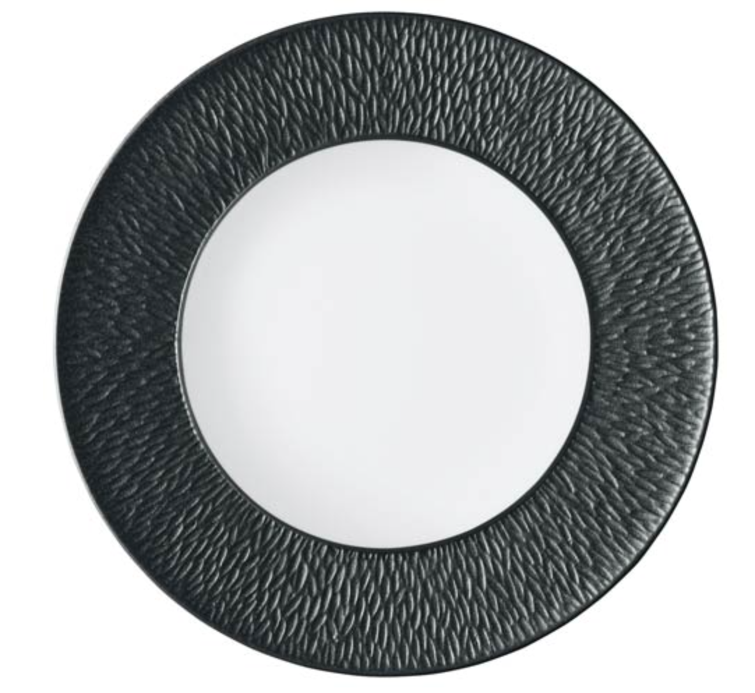 The Raynaud Mineral Irise Dinnerware - Black features a round plate with a smooth white Limoges porcelain center and a wide, textured black rim patterned with raised, irregular lines radiating outward, viewed from above.
