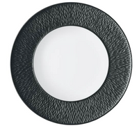 The Raynaud Mineral Irise Dinnerware - Black features a round plate with a smooth white Limoges porcelain center and a wide, textured black rim patterned with raised, irregular lines radiating outward, viewed from above.