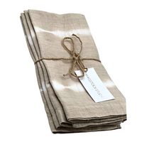 The Hand Dyed Linen Napkin Set of 4 - Bone by Whigstock Studio features folded beige linens with a subtle white tie-dye pattern, finished with a brown string and white tag—sustainable essentials for any table.