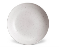 The L'Objet Terra Stone Dinnerware is a round, shallow, light gray ceramic plate with subtle dark speckles, hand-crafted for understated elegance and set against a white background.