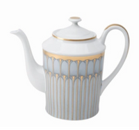 A white porcelain teapot with a curved spout and handle, adorned with gold and silver geometric patterns, from Philippe Deshoulieres’ Arcades Gold Dinnerware collection, featuring a matching lid accented with a gold rim.