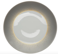 The Haviland Souffle D'or Dinnerware features a round, light gray ceramic plate with a glossy center and a gradient ring of small gold dots near the rim, blending classic Limoges-inspired elegance with modern handmade style.