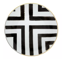 The Sol Y Sombra charger by Christian Lacroix x Vista Alegre is a round white porcelain plate with bold black intersecting lines and right angles, elegantly finished with a thin gold rim.