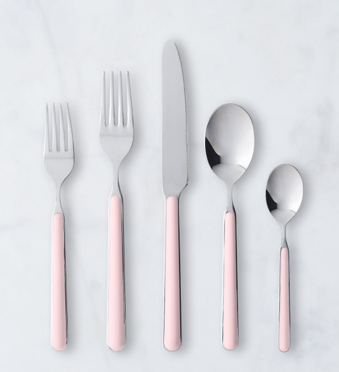 The Mepra Fantasia Flatware 5 Piece Set, shown in light pink with silver tops, features two forks, one knife, one spoon, and one teaspoon arranged side by side on a white surface.