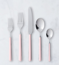 The Mepra Fantasia Flatware 5 Piece Set, shown in light pink with silver tops, features two forks, one knife, one spoon, and one teaspoon arranged side by side on a white surface.