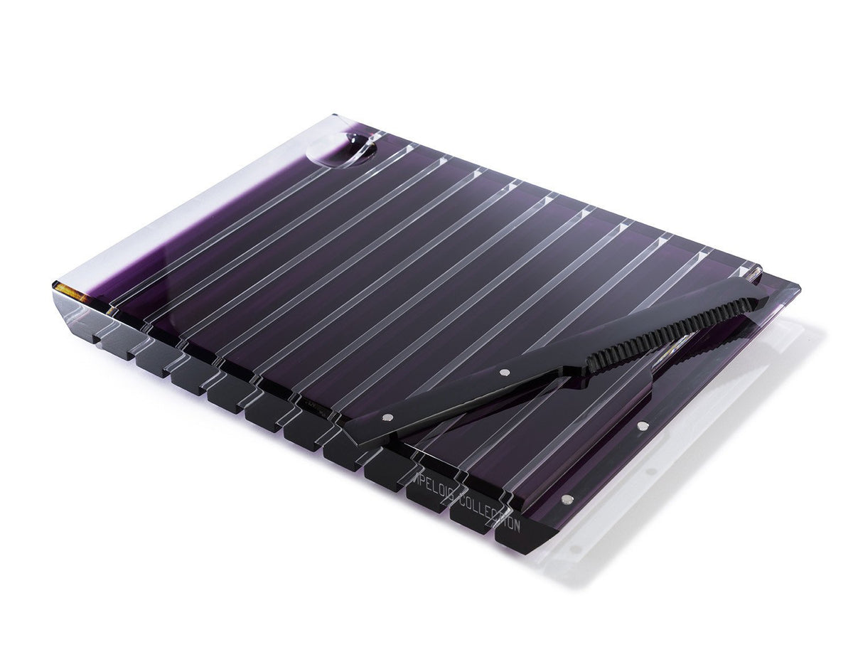 The Striped Acrylic Challah Board & Knife by Apeloig features a transparent purple design with evenly spaced grooves and a matching serrated knife, perfect for a modern table setting.