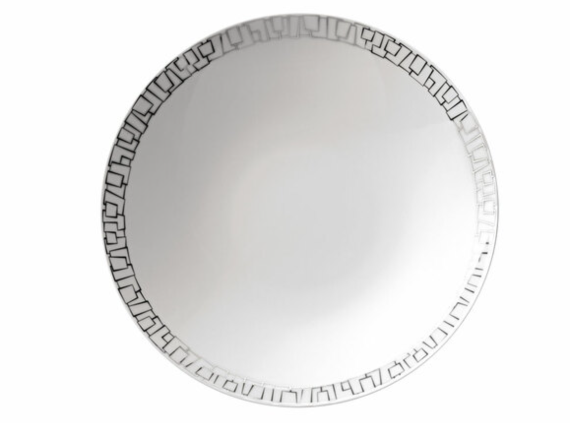 The Rosenthal Skin Platinum TAC 02 Dinnerware is a round white porcelain plate with a glossy finish, showcasing a geometric black pattern and subtle platinum accents on the rim.