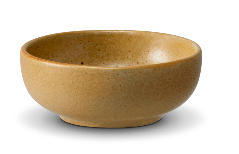 The Terra Leather Dinnerware by L'Objet is a small, round, light brown ceramic bowl with a smooth, slightly speckled glazed finish, shown on a white background.
