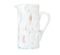 The Kim Seybert Gala Pitcher White is a tall, clear pitcher with a side handle, featuring a white, textured speckled pattern and subtle color accents that highlight the elegance of Murano-style glass.