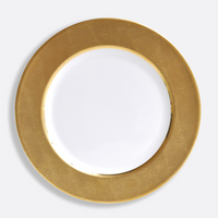 The Sauvage Gold Dinnerware by Bernardaud features a round white Limoges porcelain plate with a wide, embossed gold snake skin rim, displayed on a plain light gray background.