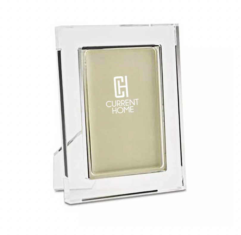 The Tizo Matte Lip Frame Clear is a modern clear rectangular glass or acrylic photo frame with a gold backing and white Current Home logo on the front, standing upright for a chic and elegant display.