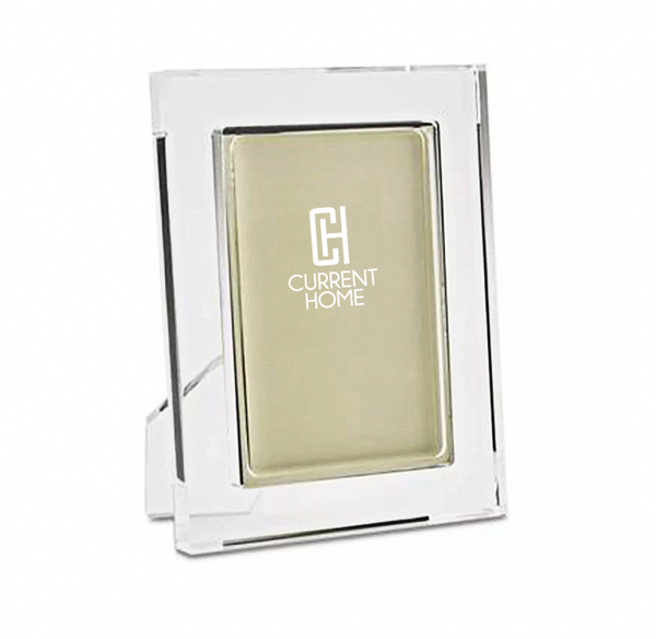 The Tizo Matte Lip Frame Clear is a modern clear rectangular glass or acrylic photo frame with a gold backing and white Current Home logo on the front, standing upright for a chic and elegant display.