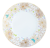 The Fèerie by Michael Cailloux plate from Bernardaud features a gold rim, golden dandelion-like flowers, colorful blooms, a blue hummingbird, and butterfly—showcasing exquisite Limoges porcelain craftsmanship.