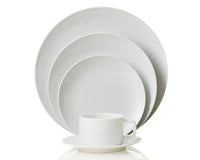 The Organza White Dinnerware set by Bernardaud, crafted in Limoges porcelain, features a subtle texture and includes dinner, salad, bread plates, plus cup and saucer—ideal for minimalist décor.