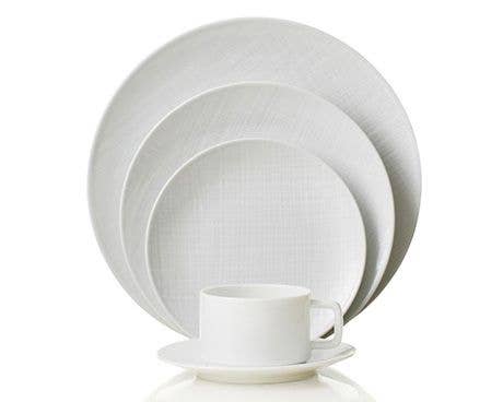 The Organza White Dinnerware set by Bernardaud, crafted in Limoges porcelain, features a subtle texture and includes dinner, salad, bread plates, plus cup and saucer—ideal for minimalist décor.