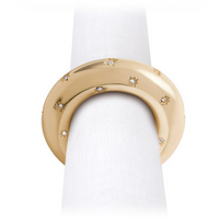 A neatly rolled white napkin is held by a L’Objet Stars Napkin Jewels ring, 24k gold plated with star engravings and Swarovski crystals, bringing elegant sparkle to your table. Set of 4.