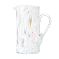 The Kim Seybert Gala Pitcher White is a glass pitcher with a handle, featuring a white textured pattern, subtle multicolored spots, and a glossy, slightly translucent finish.