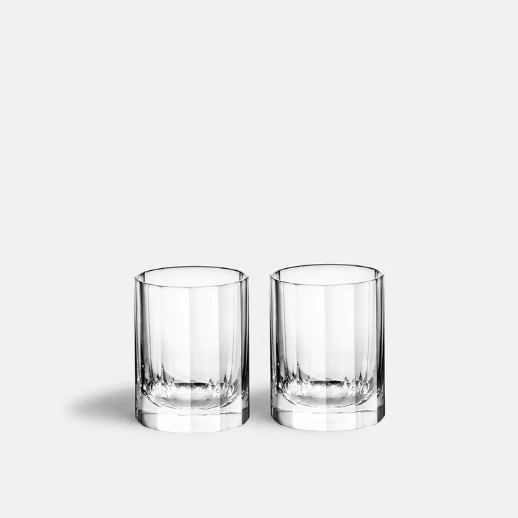 Two clear, empty Richard Brendon Fluted Shot Glasses (set of 2) are placed side by side on a plain light gray background, casting soft shadows to the left.